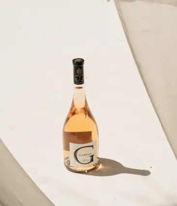 Bouteille de rosé Garrus posée sur une surface en pierre avec des ombres