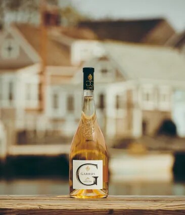 Garrus rosé bottle placed on a table with a blurred estate building in the background