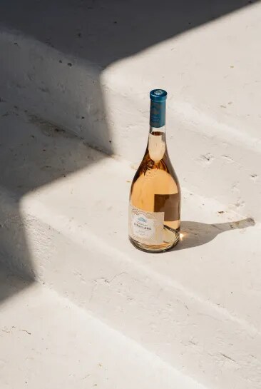 Château d’Esclans rosé bottle placed on stone steps in natural sunlight with shadows