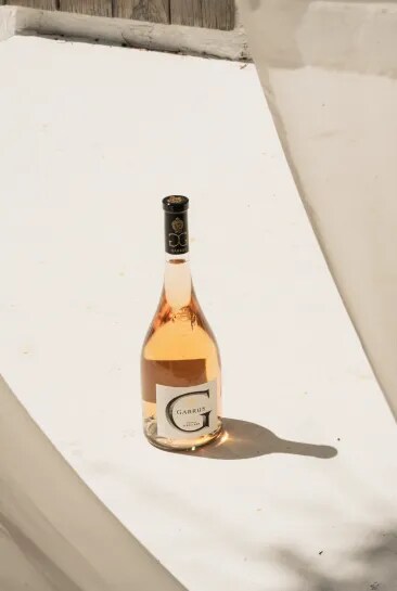 Garrus rosé bottle placed on a stone surface in natural sunlight with defined shadows
