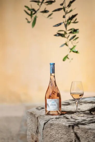 Bouteille de rosé Château d’Esclans posée sur de la pierre avec un verre.