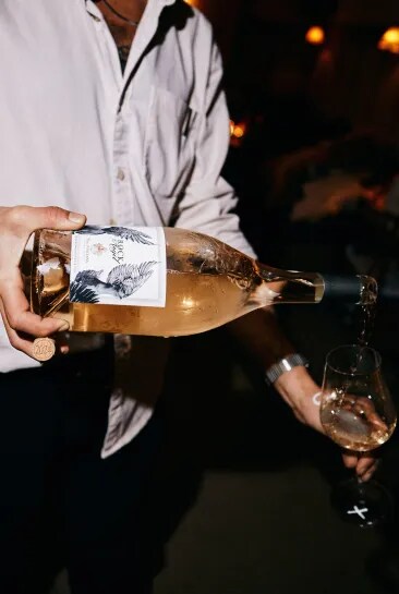 Rock Angel bottle pouring wine into a glass in a dimly lit setting