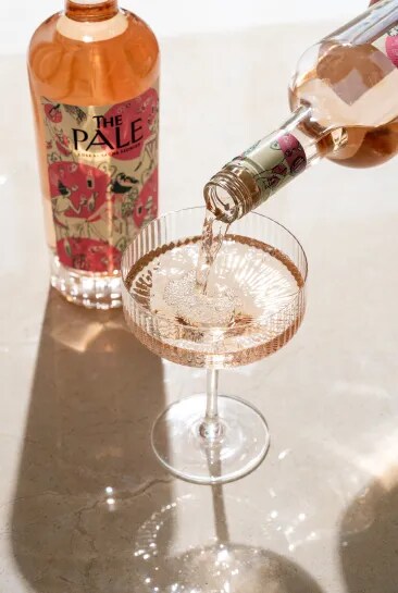 The Pale rosé poured into a glass with another bottle visible in the background