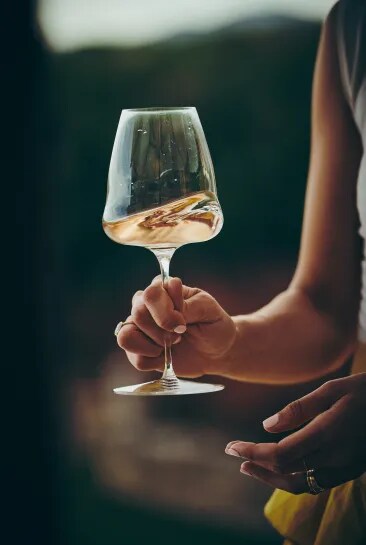 Gros plan sur une main tenant un verre de vin rosé en extérieur