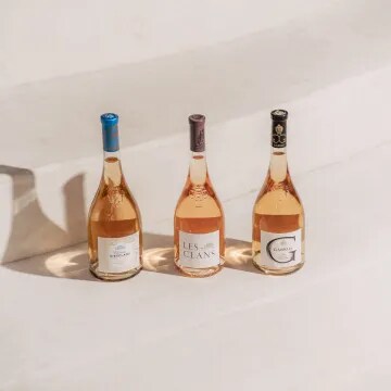 Three Château d’Esclans rosé bottles displayed together on sunlit stone steps