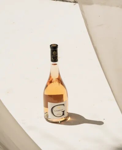 Bouteille de rosé Garrus posée sur une surface en pierre avec des ombres